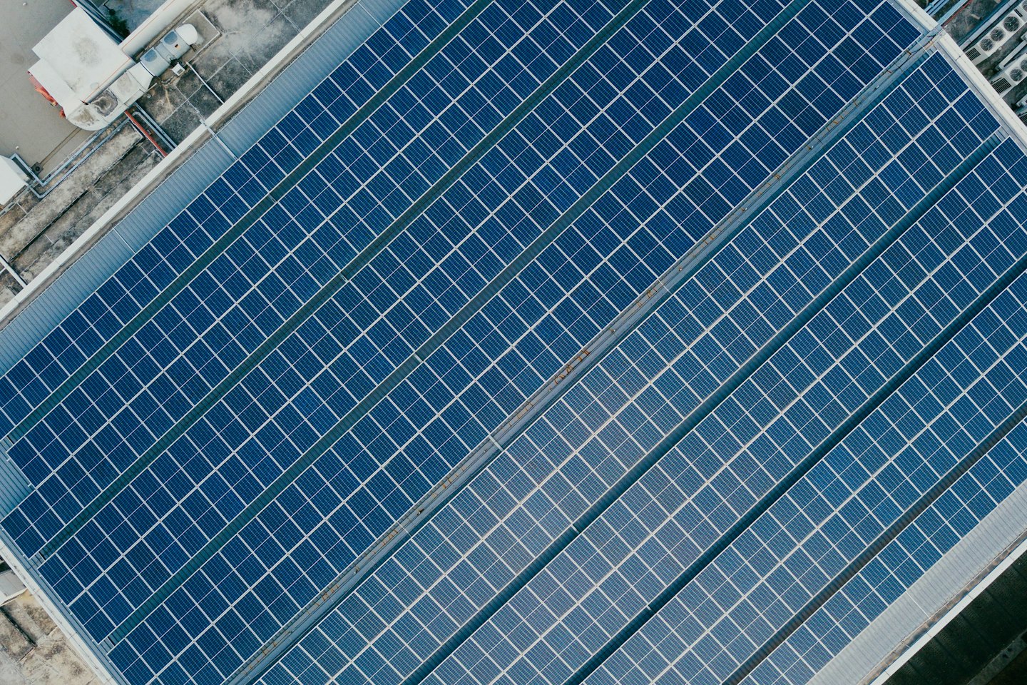 Paneles solares azules cubriendo la azotea de un gran edificio comercial.