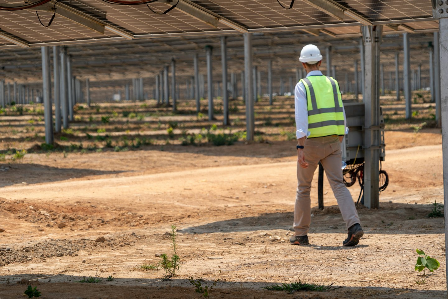 Técnico con casco inspecciona una granja solar.
