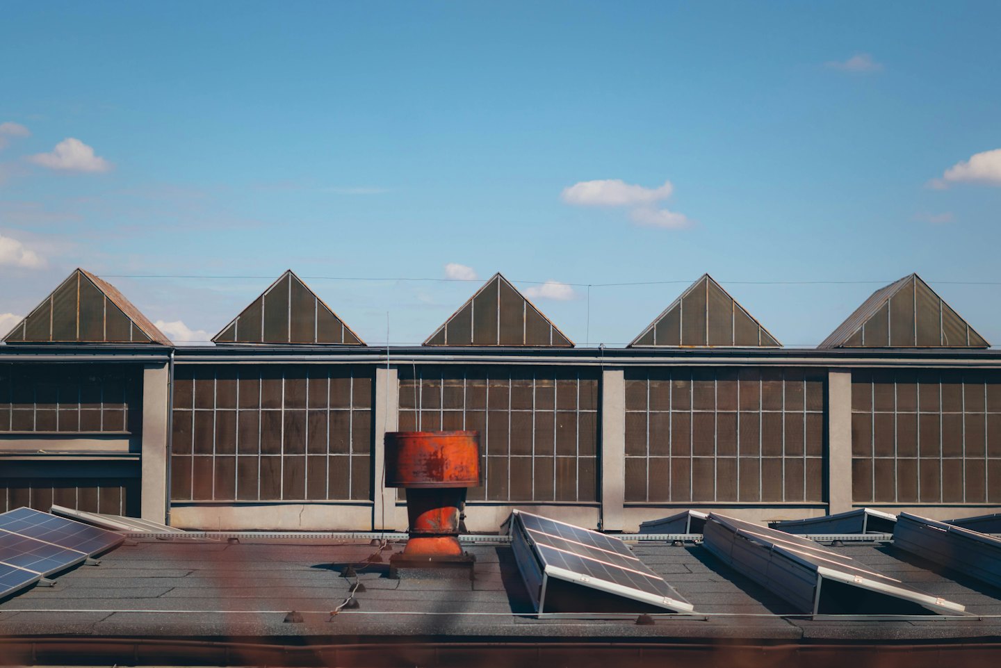Tejado de edificio industrial con paneles solares y tragaluces.